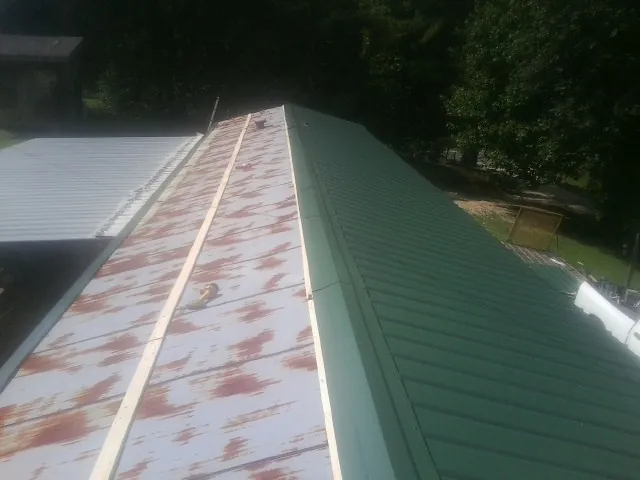 Old rusted panels beside newly installed green metal roofing — Wind Damage Roof Repair by Roofing Brothers in Mc Kenzie