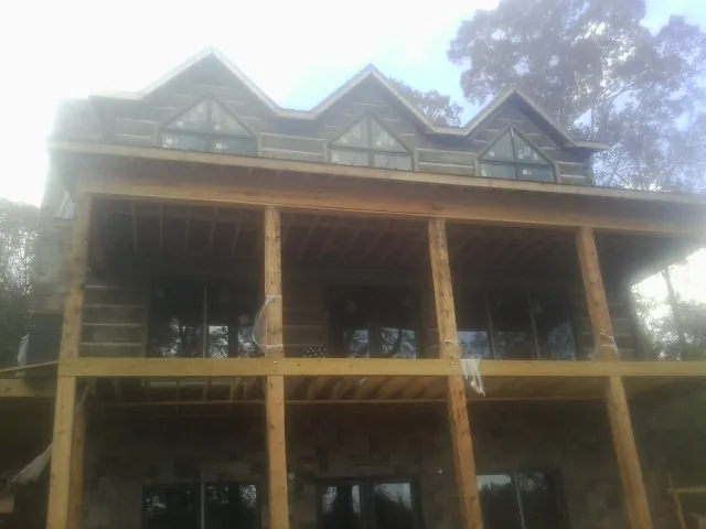 Dormers and porch framing on a large log home under construction — Roof Coating work by our crew in Mc Kenzie