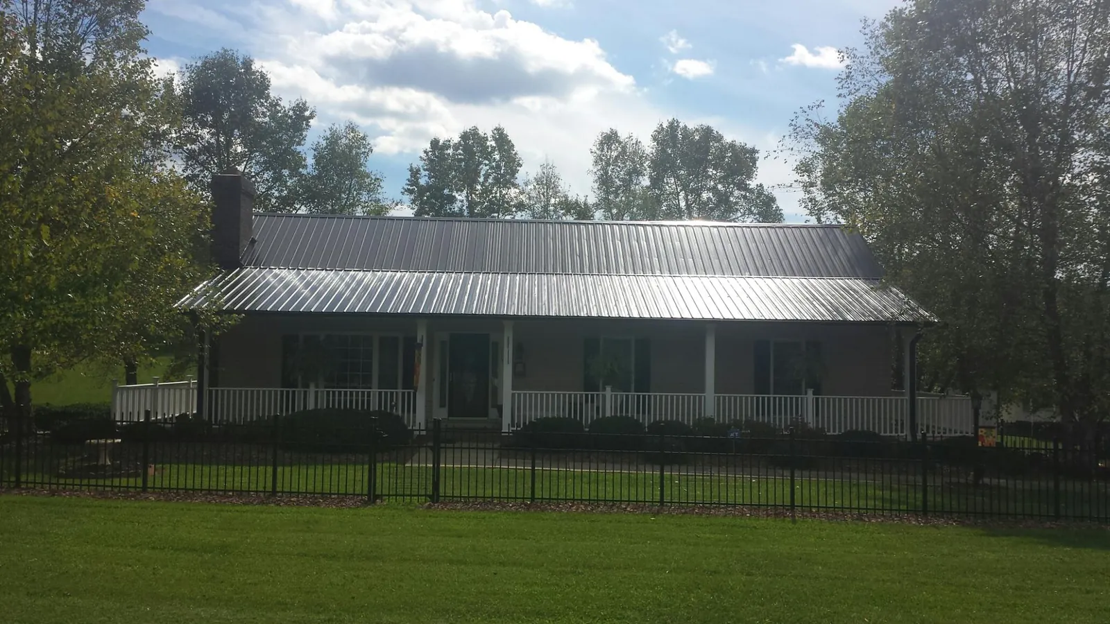 Gray metal roof on a brick ranch with a full width front porch — Gutter Guard Installation work by our crew in Mc Kenzie