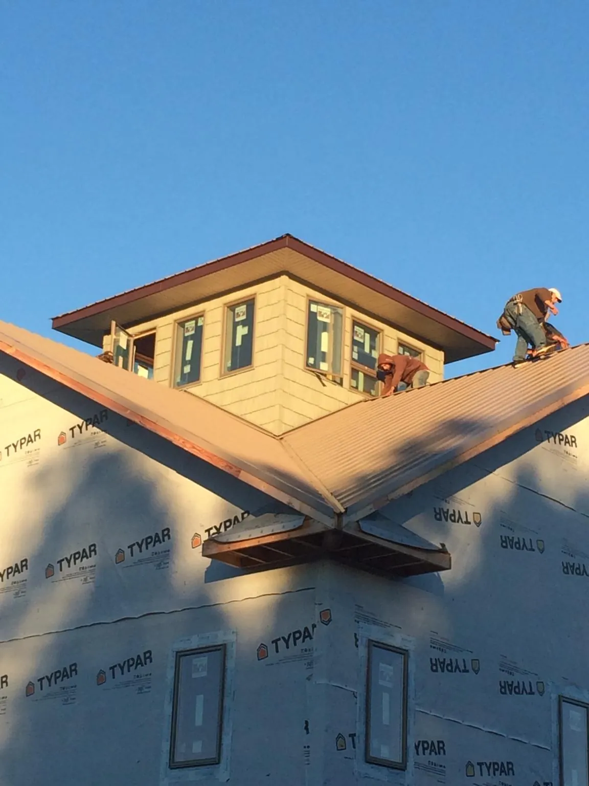 Roofers working around a rooftop cupola on a new metal roof at sunset — Roof Waterproofing in Mc Kenzie by Roofing Brothers